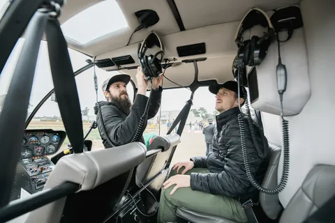 Two of the crew in a helicopter cockpit, headsets on