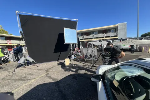 Flags, lights and a camera car in a motel parking lot