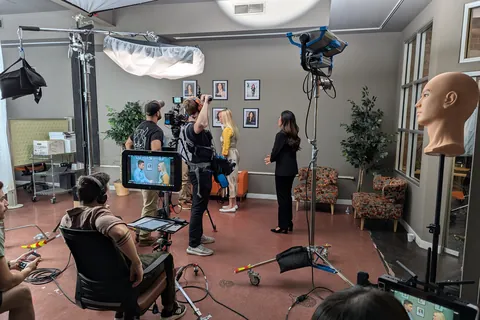 A camera operator on a stabilizer rig, lights and video village on an office set
